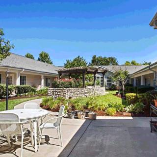 A tranquil courtyard with outdoor seating and a well-maintained garden on a sunny day.