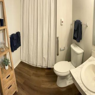A clean and organized bathroom with a shower, toilet, and sink.