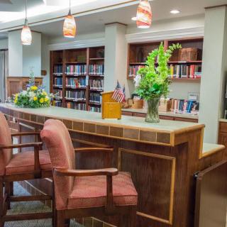 A cozy library reading area with a wooden counter and bookshelves in the background.