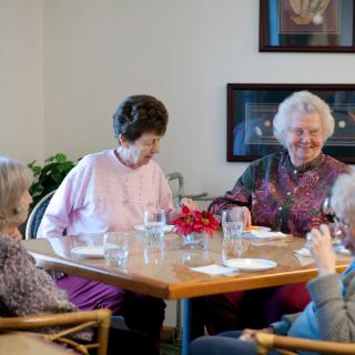 A group of seniors socializing around a dining table.