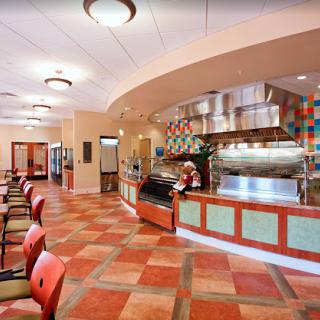 A modern restaurant interior with a dining area, featuring colorful tile flooring and stylish lighting fixtures.