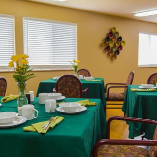 A cozy dining area set up for a meal with green tablecloths and decorative flowers.