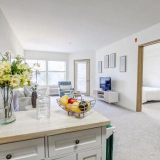 A bright and modern living room with a stylish design, featuring a fruit bowl and fresh flowers on the table.