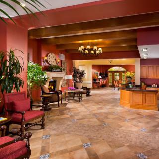 A warmly decorated hotel lobby with comfortable seating and greenery.