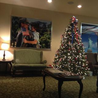 A warmly lit room features a beautifully decorated Christmas tree, surrounded by cozy furnishings and festive decor.