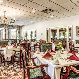 An elegant restaurant dining room with neatly set tables and a chandelier overhead.