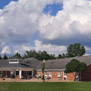 A scenic view of a modern building surrounded by green grass, under a cloudy sky.