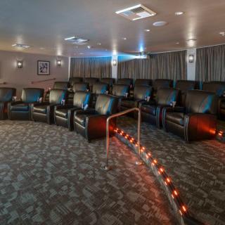 A cozy home theater with rows of leather recliners and a large projector screen.