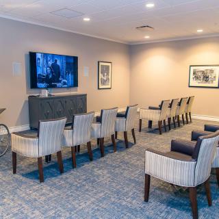 A cozy home theater setup with multiple rows of chairs facing a large television.