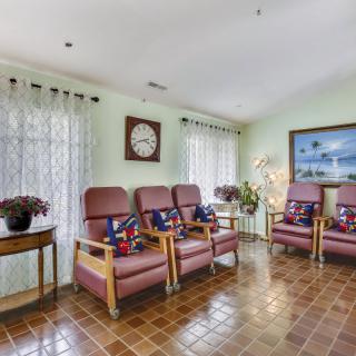 A cozy waiting room featuring comfortable chairs, a decorative clock, and a serene painting on the wall.