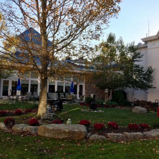 A scenic view of a garden with outdoor seating and a building in the background during autumn.