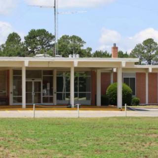 The front entrance of a brick school building surrounded by trees.