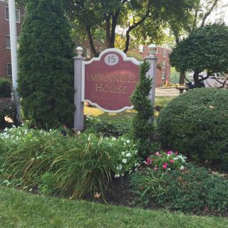A landscaped garden with a decorative sign surrounded by greenery and flowers.