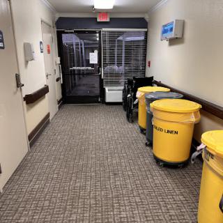 A view of a hallway featuring yellow trash bins, typical in a medical or healthcare environment.