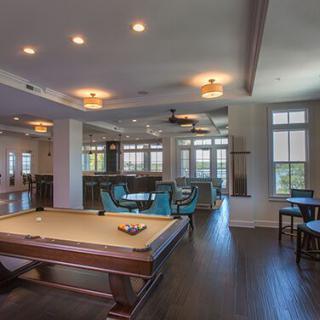 A modern game room featuring a billiards table and comfortable seating with ample natural light.