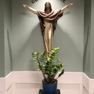 A serene indoor setting featuring a religious statue and a decorative plant.