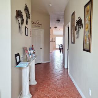 A decorated hallway with tile flooring, featuring wall art and a small console table.
