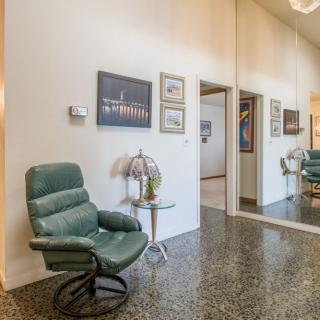 A cozy living room featuring a green chair, artwork on the walls, and reflective flooring.