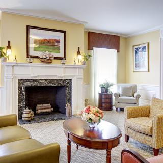 A cozy living room with a classic fireplace, comfortable armchairs, and elegant decor.