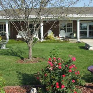 A well-maintained garden area with a variety of plants and flowers in front of a building.