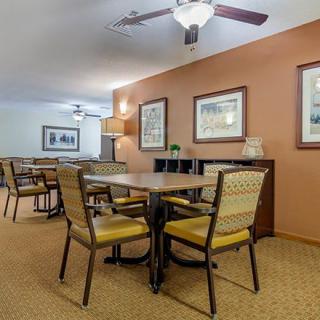 A cozy dining area with neatly arranged tables and chairs, soft lighting, and wall decorations.