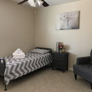 A minimalist bedroom with a single bed, gray-toned decor, and a cozy armchair.