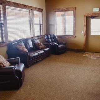 A cozy living room with leather seating and large windows.