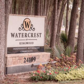 Entrance sign for Watercrest at Kingwood, surrounded by trees and landscaping.