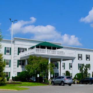 A modern hotel featuring a white exterior, green awning, and a clear blue sky.