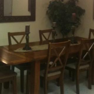 A cozy dining room featuring a wooden table with matching chairs, a decorative mirror, and candle holders.