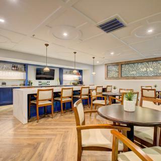 A modern restaurant interior with a bar counter and dining tables.
