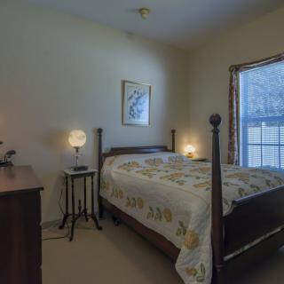 A cozy bedroom with a large wooden bed and soft lighting from bedside lamps.