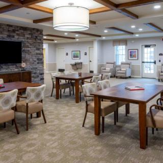 A modern dining and living space featuring wooden tables, comfortable chairs, and warm lighting.