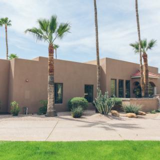 A modern desert home with palm trees and cacti in the foreground.