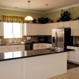 A modern kitchen featuring white cabinets and stainless steel appliances.