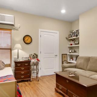 A cozy living room with a couch, coffee table, and bookshelves, complemented by warm wooden flooring and a lamp.