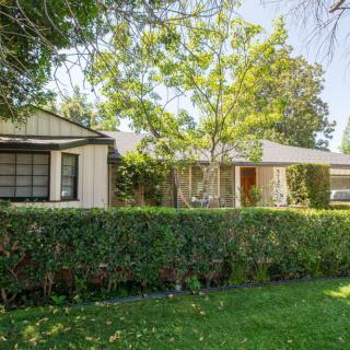 A suburban house with a lush green yard and surrounding trees.