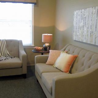 A cozy living room with sofas, cushions, and a warm lamp.