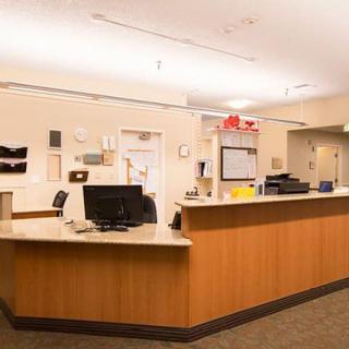 A reception desk in a well-lit office environment, featuring computers and organized workspace.