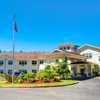A residential building with well-maintained landscaping and a flagpole on a sunny day.