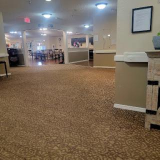 A view of a spacious hallway in a residential or commercial building, featuring carpeted flooring and warm lighting.