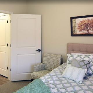 A cozy bedroom with a bed, patterned bedding, and a picture frame on the wall.