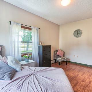 A cozy bedroom with a bed, chair, and window providing natural light.