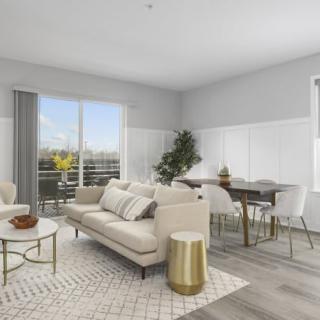 A modern living room with a cozy sofa, coffee table, and an adjacent dining area, decorated in neutral tones.