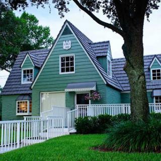 A charming green house with a welcoming front yard and a unique architectural design.