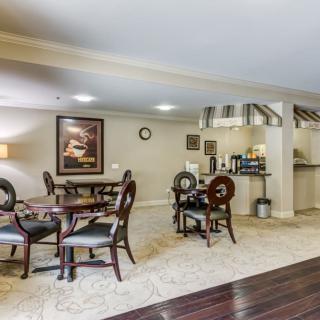 A cozy dining area with multiple tables and chairs, featuring artwork on the walls and a mix of carpet and hardwood flooring.