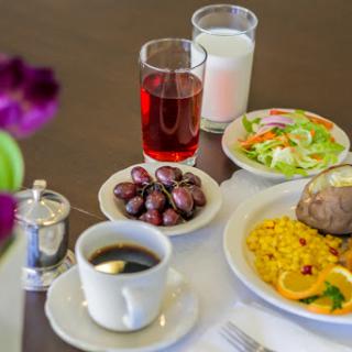 A delicious breakfast spread featuring coffee, a refreshing salad, sweet dates, a glass of juice, and fluffy rice.