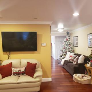 A cozy living room with festive Christmas decorations and a large TV on the wall.