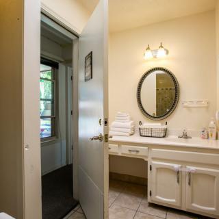 A clean and bright bathroom with a mirror, sink, and neatly stacked towels.