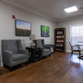 A cozy waiting area with comfortable seating, a bookshelf, and large paintings on the wall.